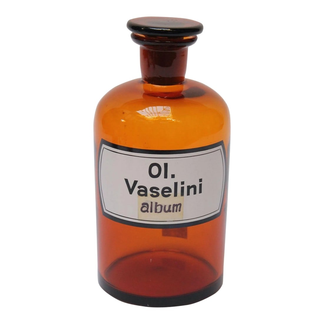 Vintage German Amber Glass "Ol. Vaselini" Apothecary Bottle: Ol. Vaselini' pharmacy bottle / apothecary jar (circa late 1920s / early 1930s, Germany). Amber glass with button stopper and enamel label. "86" is etched into the bottle itself and stopper, as shown 