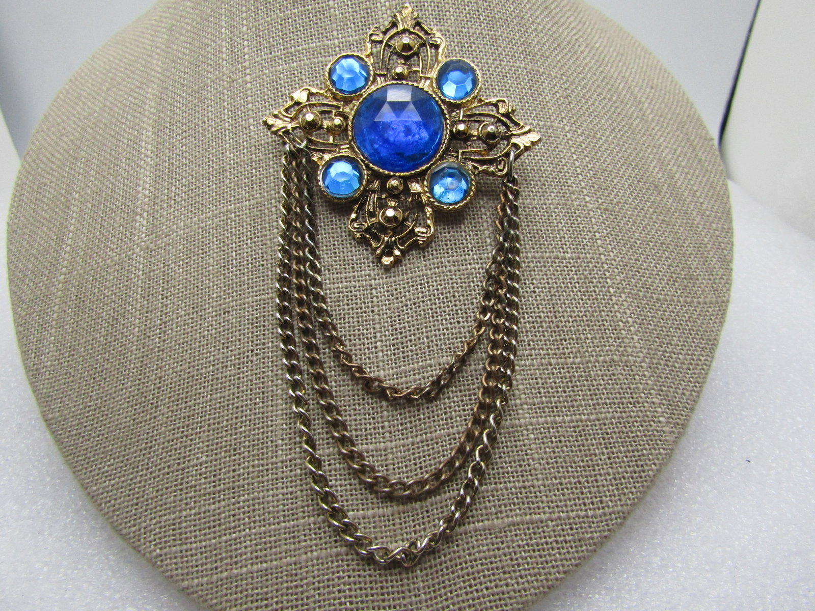 Vintage Blue Rhinestone Brooch, Chain Dangles, 4.5" by 2", 1980's.: Title: Vintage Blue Rhinestone Brooch, Chain Dangles, 4.5" by 2", 1980's. Description: Vintage Blue Rhinestone Brooch, Chain Dangles, 4.5" by 2", 1980's. It is gold tone with four points somewhat