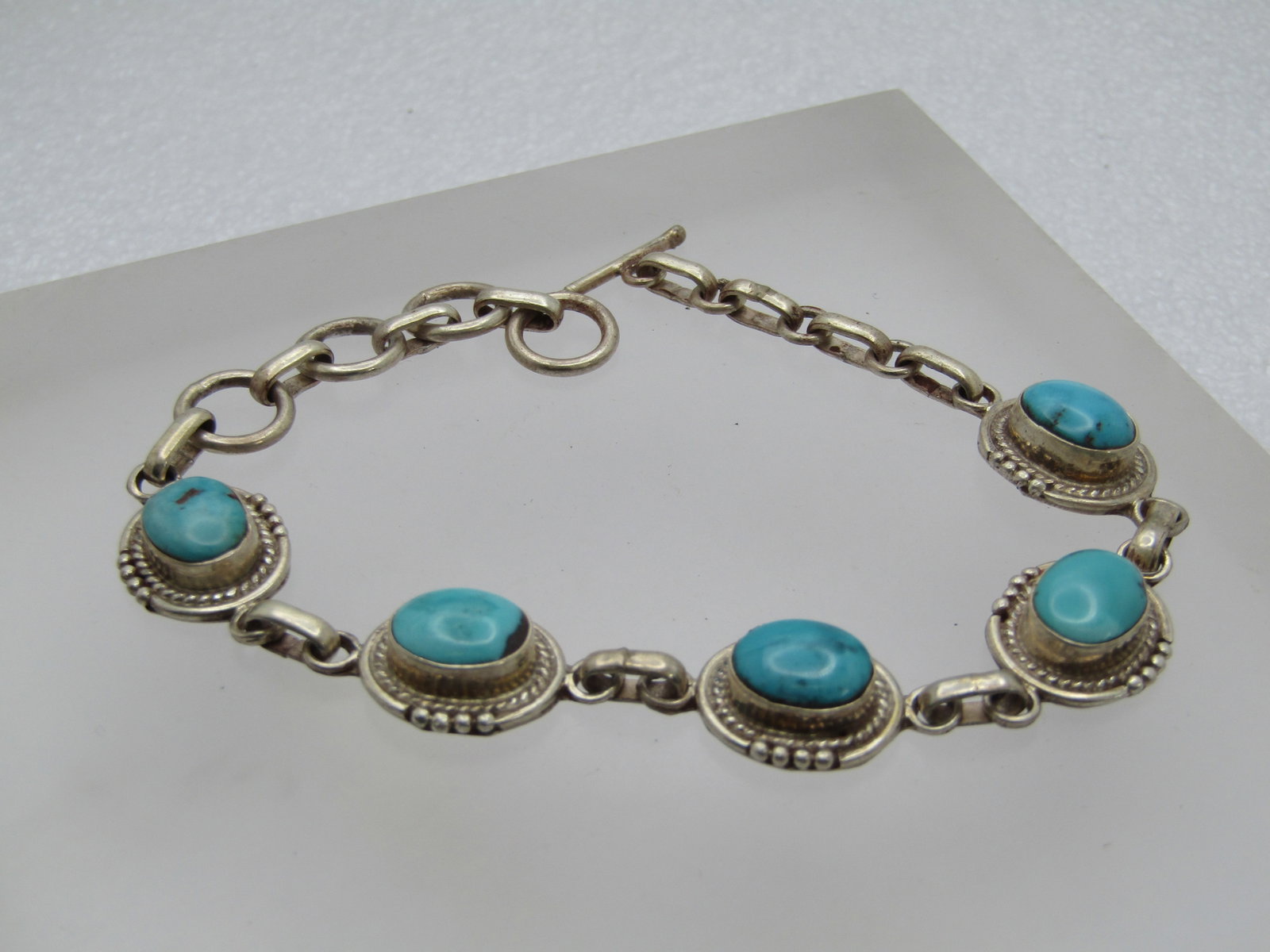 Vintage Sterling Southwestern Turquoise Bracelet, Toggle Clap, 8": Vintage Sterling Southwestern Turquoise Bracelet, Toggle Clap, 8". ThEre are five links with a t urquoise bezel-set stone that is appx. 9.5mm by 8mm. It has a rope accent with a wider base with beaded