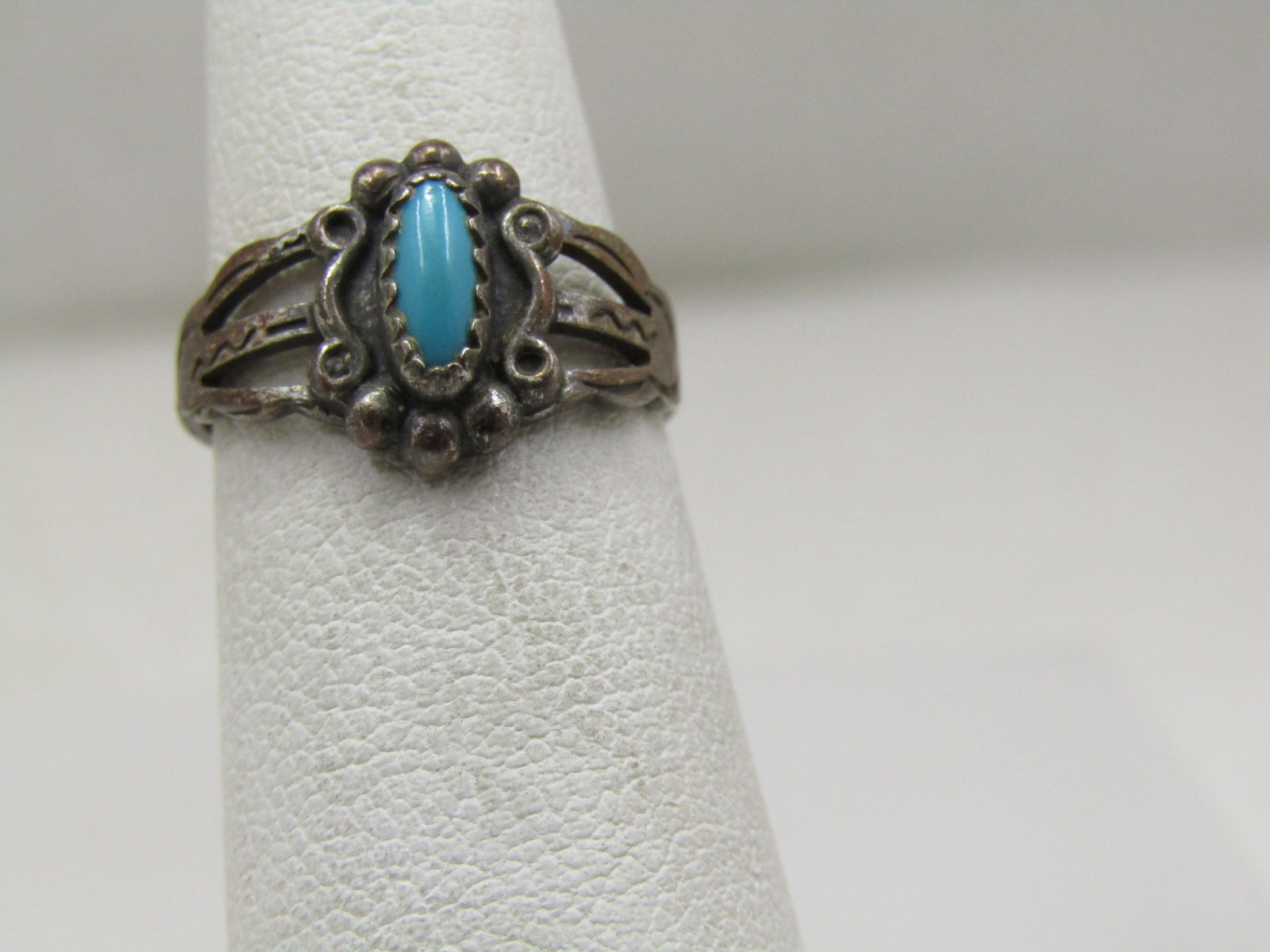 Vintage Sterling Southwestern Turquoise Ring, Sz 4.5, 1960's-1970's: Vintage Sterling Southwestern Turquoise Ring, Sz 4.5, 1960's-1970's. There is a bezel-set turquoise stone that is appx. 7mm by 3.5mm in the center with a scrolled and beaded frame around it. The top o