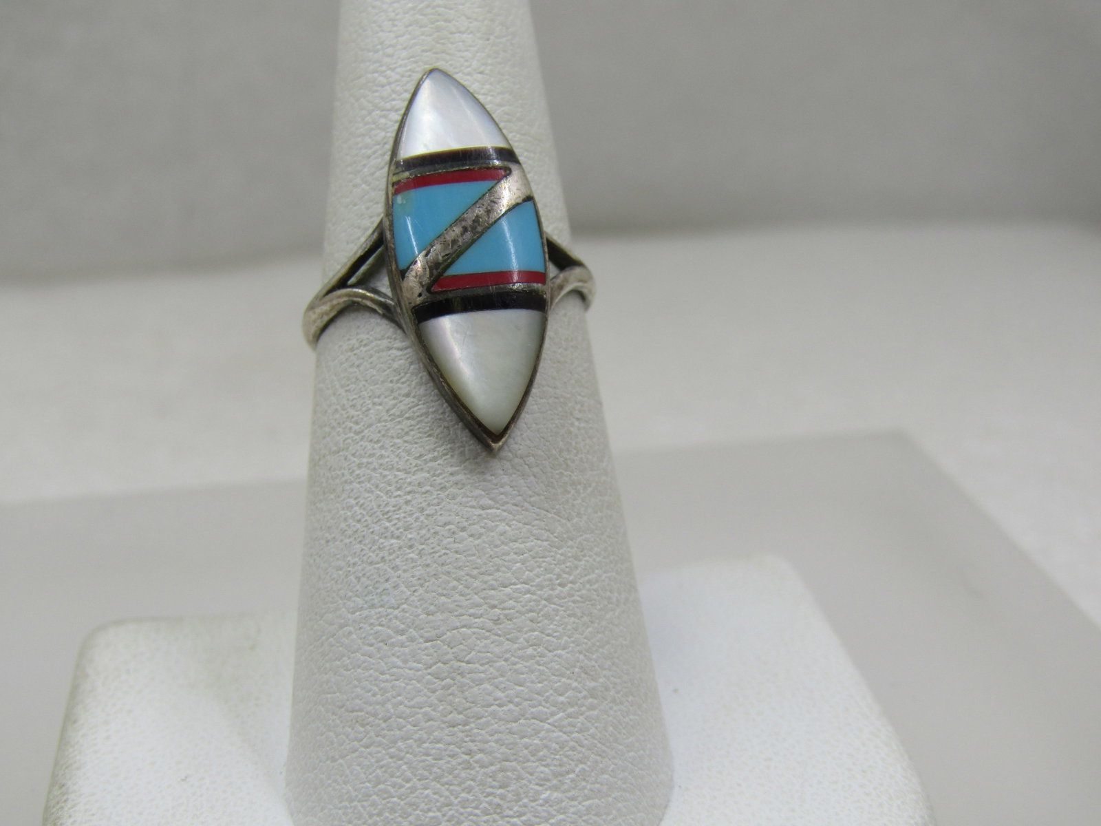 Vintage Sterling Southwestern Inlaid Ring, Pointed Sz. 6.5: Vintage Sterling Southwestern Inlaid Ring, Pointed Sz. 6.5. Inlaid mother-of-pearl, turquoise, red coral, onyx. The top of the ring is 1" long and 3/8" wide with a sivler inlaid diagonal accent dividi
