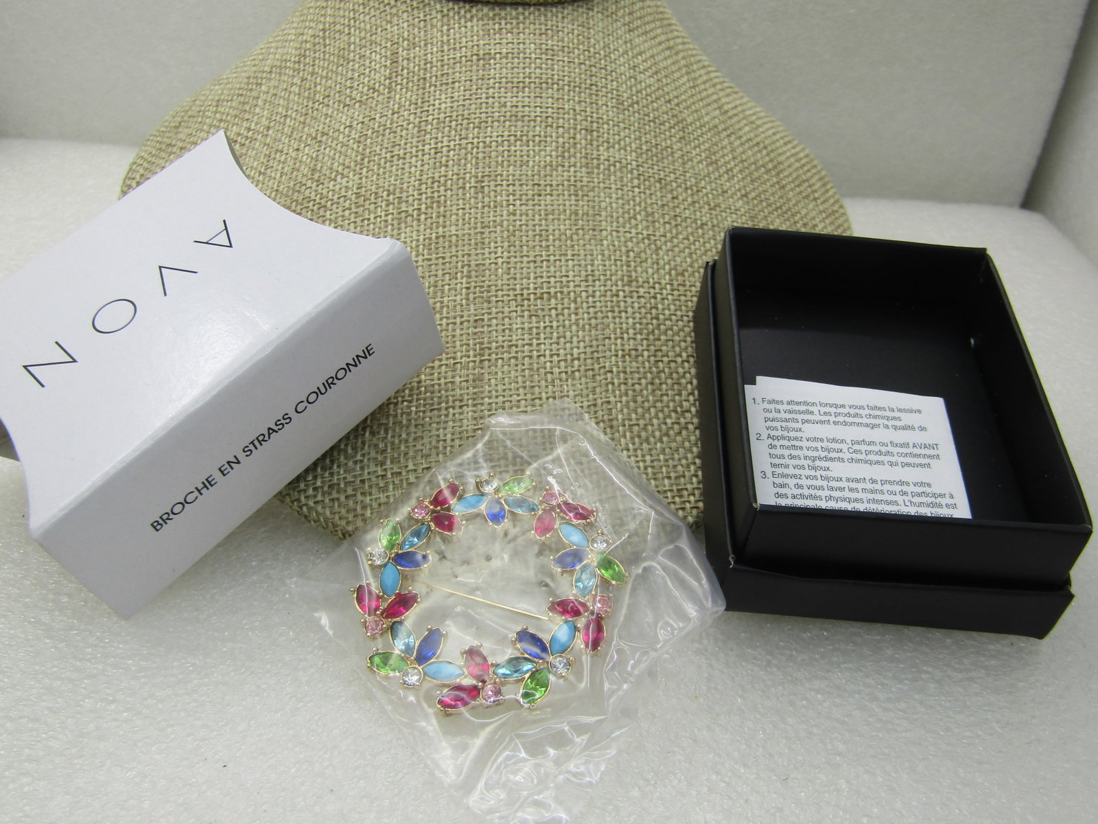 Avon Rhinestone Wreath Brooch, New in Box, Gold-Tone, Unopened: Avon Rhinestone Wreath Brooch, New in Box, GoldTone, Unopened. 1.75" wide with pink, red, green, turquoise, blue, green, clear rhinestones in a floral pattern creating the wreath. In original black bo