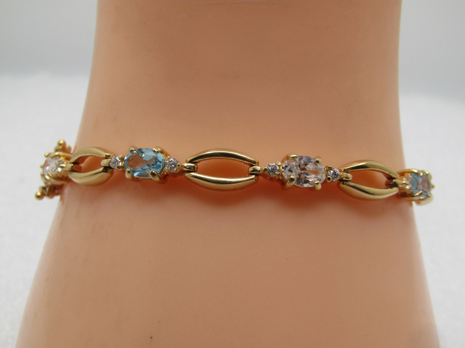 Blue Topaz & Clear CZTennis Bracelet, Gold tone, 7.5", 1990's: Blue Topaz & Clear CZTennis Bracelet, Gold tone, 7.5", 1990's. This is not signed or marked. Gold tone/plated with oval stones that test as blue topaz - likely lab grown which is not glass or crystal 