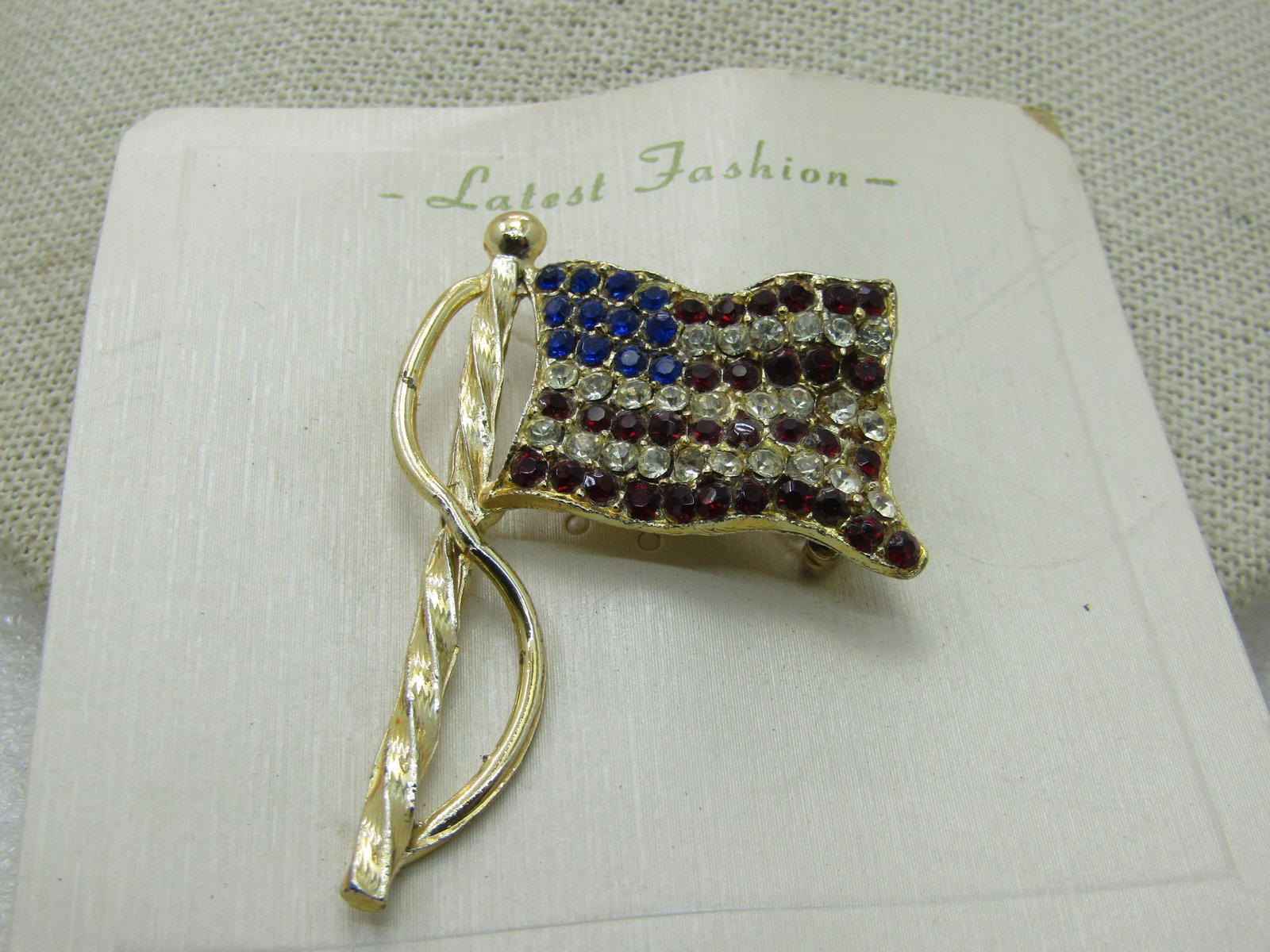 Vintage Blue & Clear Rhinestone USA Flag, Gold Tone, Brooch 2" by 1.5": Vintage Blue & Clear Rhinestone USA Flag, Gold Tone, 2" by 1.5", Vintage new on card marked Latest Fashion, sold at Nichols, long defunct store. Very good condition. (INV. W.82920.6 SS2685 J LD 10/8/2