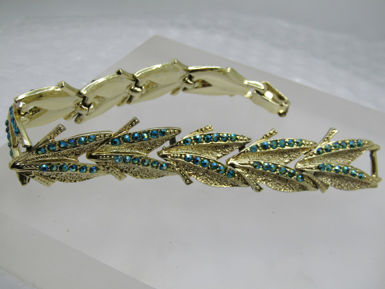 Vintage AB Peacock Rhinestone Leaf Bracelet, 7.5", 1960's: Vintage AB Peacock Rhinestone Leaf Bracelet, 7.5", 1960's. It is papx. 3/4" wide. Gold tone with textured leaf-like links that have two angled rows of peacock blue aurora borealis rhinestones that
