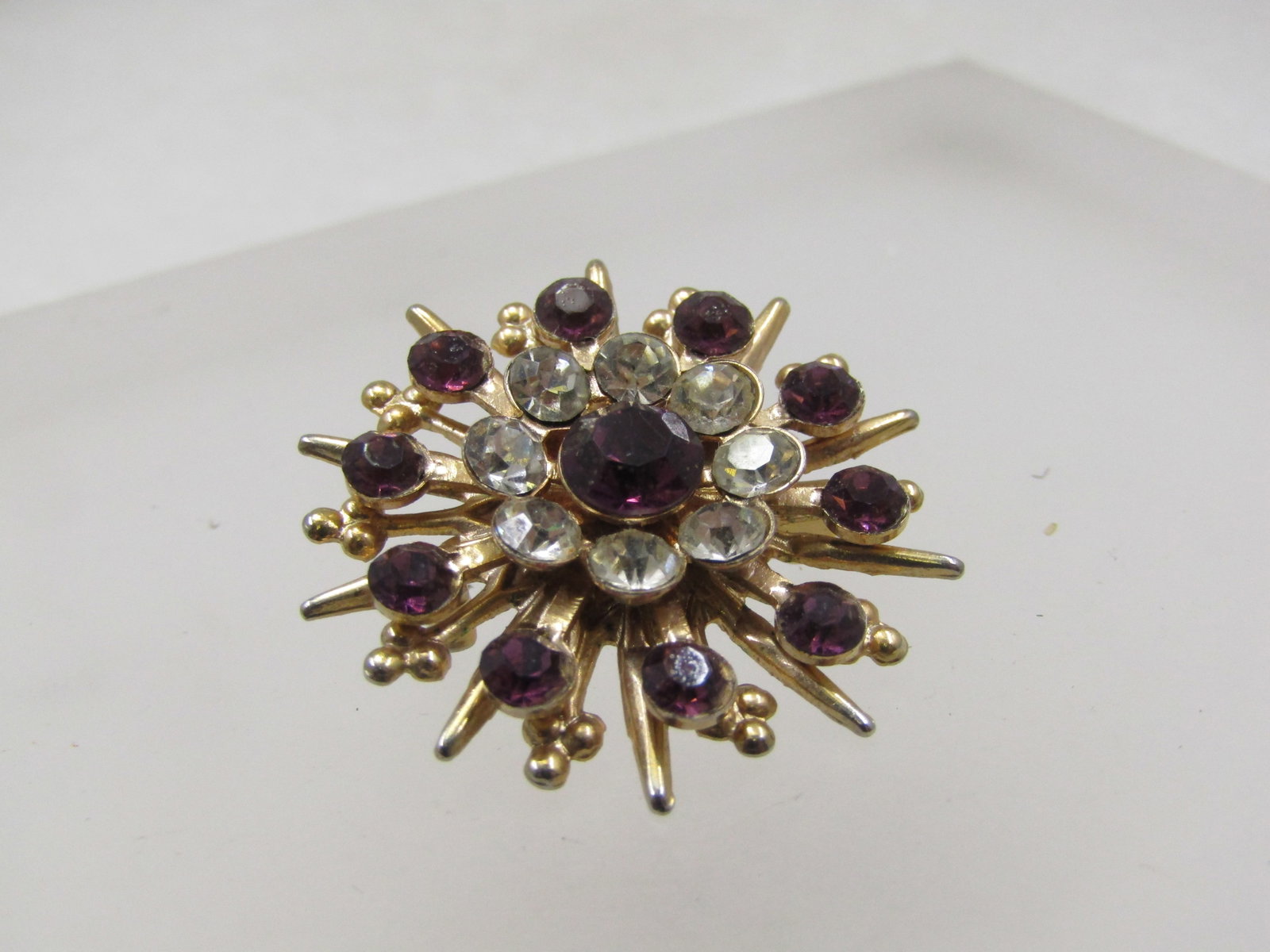 Vintage Purple & Clear Rhinestone Brooch, Starburst, 1940's-1950's: Vintage Purple & Clear Rhinestone Brooch, Starburst, 1940's-1950's in a starburst design with tiered levels of rays, purple round stones on the second layer with 3.5mm round purple rhinestones. Above 