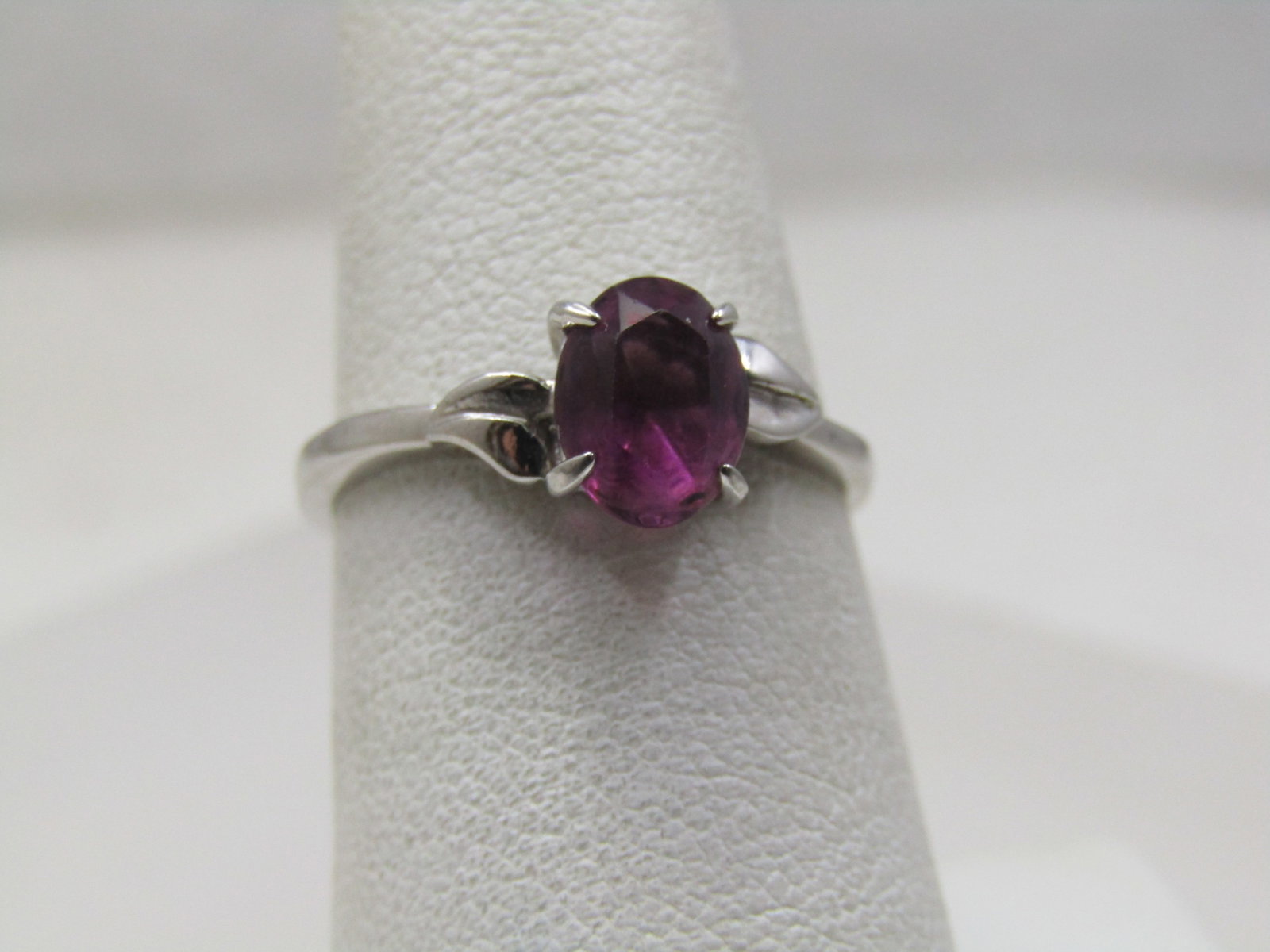Vintage Silver Tone Purple Stone Ring, Sz. 7.5, Signed DAO: Vintage Silver Tone Purple Stone Ring, Sz. 7.5, Signed DAO. The ring has an amethyst colored stone, oval that is appx. 7.5mm by 5mm. There is a raised leaf-like accent on each side of the stone that s