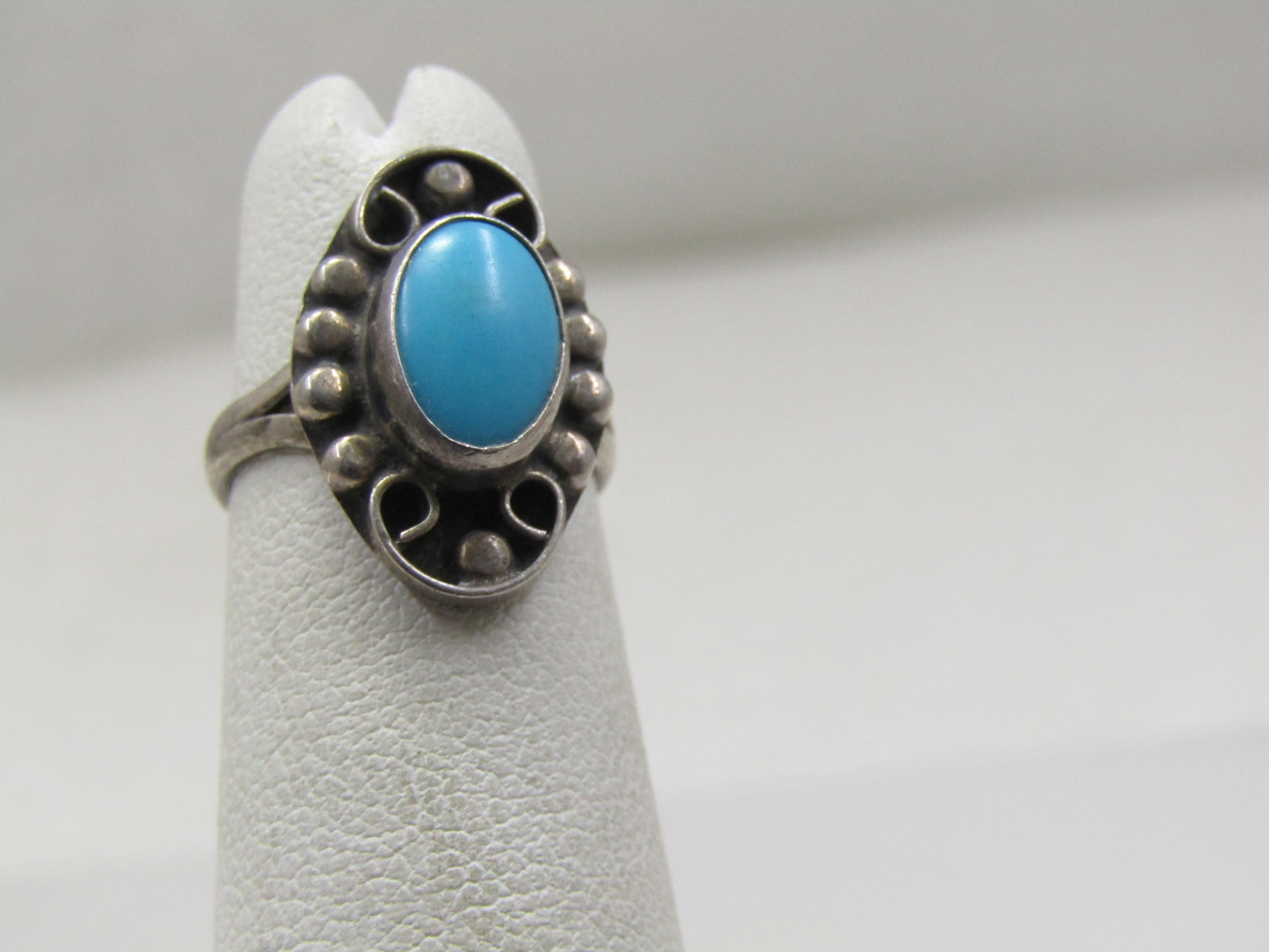 Vintage sterling Southwestern Faux Turquoise Ring, Sz. 3: Vintage sterling Southwestern Faux Turquoise Ring, Sz. 3. this has a scrolled top with beaded accents and a raised bezel-set oval turquoise created stone, likely resin. It is appx. 9.5mm by 7mm. It ha