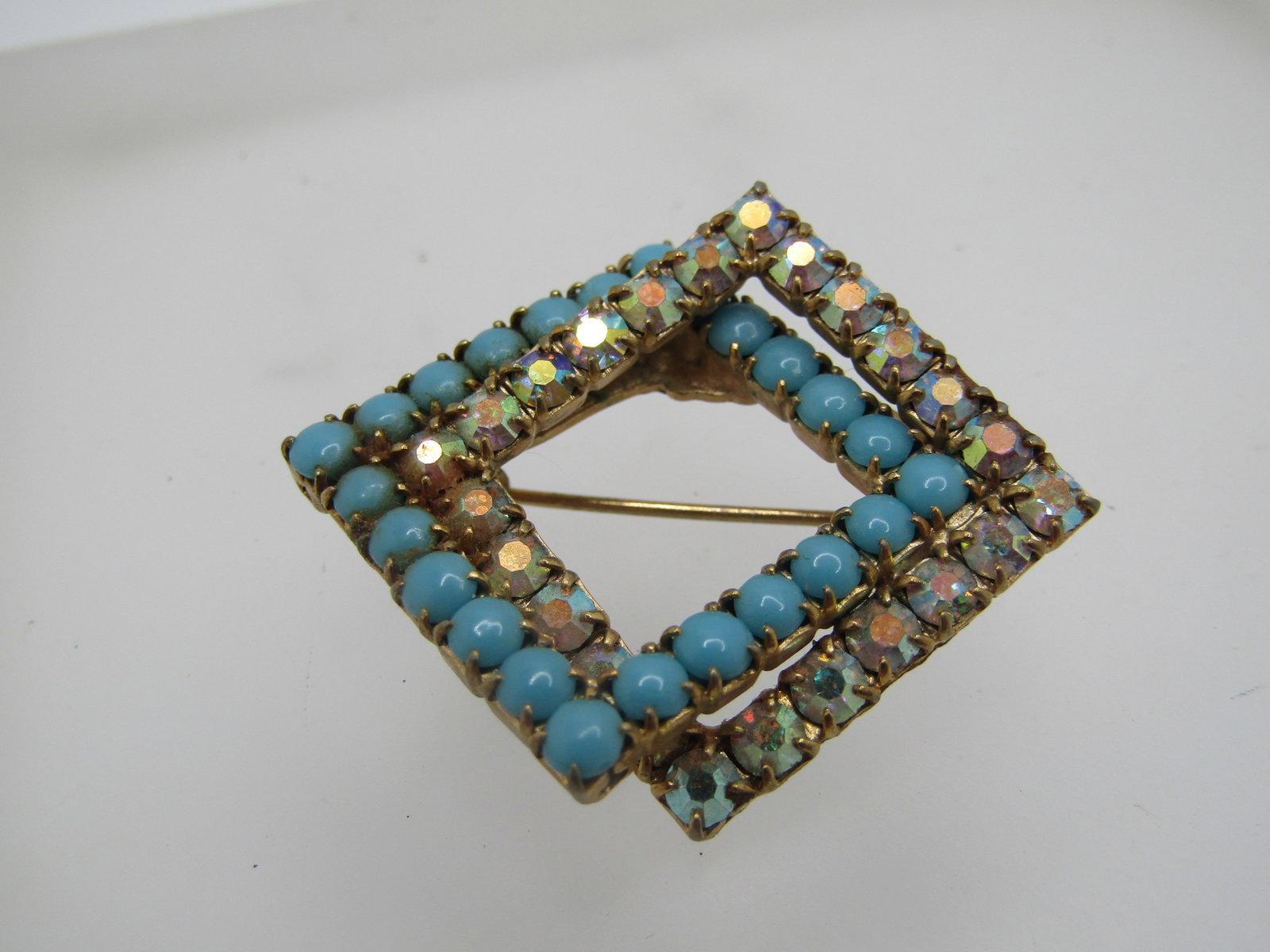 Vintage Turquoise and AB Glass Square Brooch, 1950s-1960's: Vintage Turquoise and AB Glass Square Brooch, 1950s-1960's. This is two overlapping square framed brooch design with 7/8" squares that overlapp - a turquoise class one and a clear aurora borealis one.