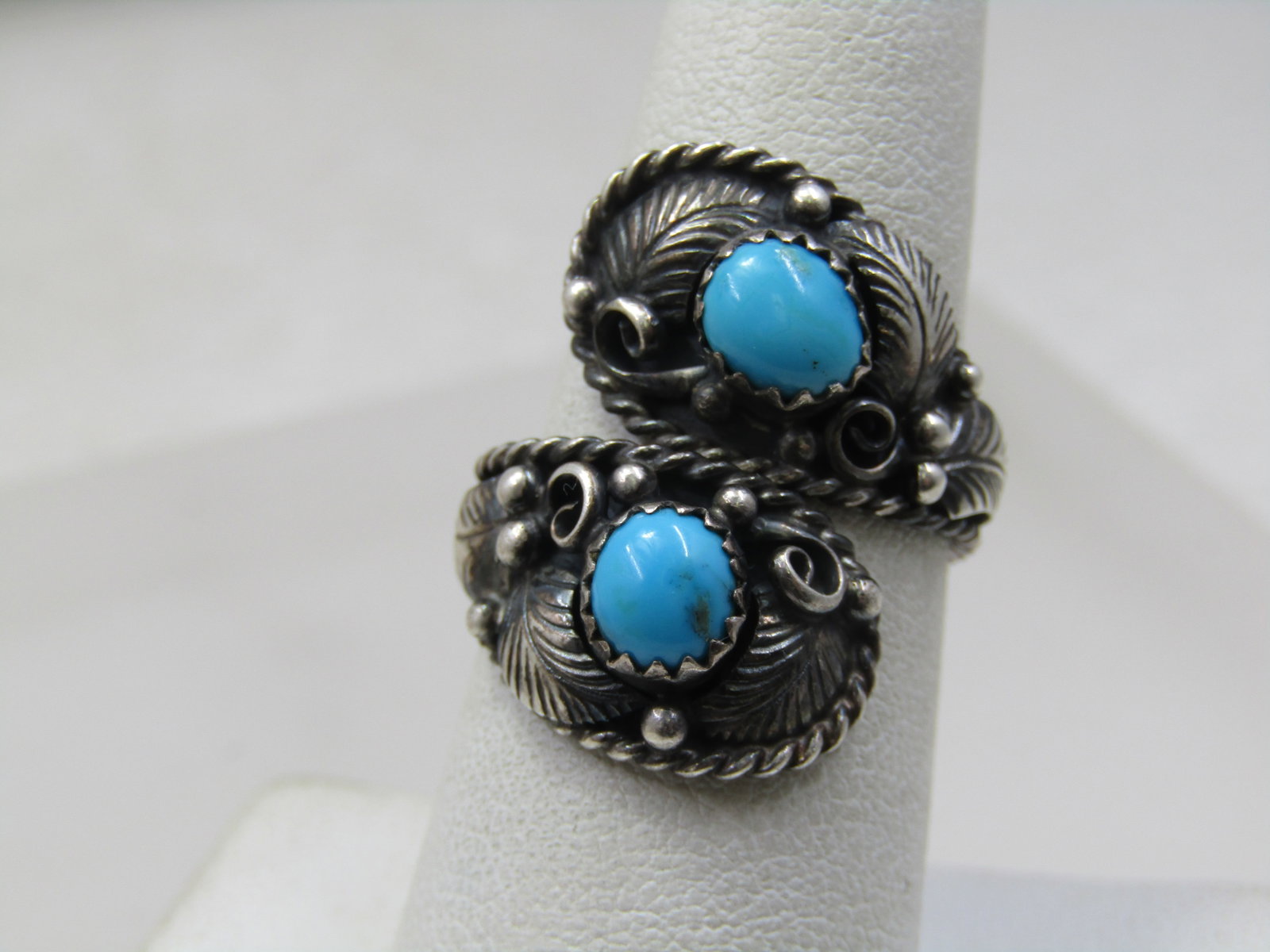 Vintage Sterling Southwestern Bypass Ring, Adj. SZ-9, Unisex, Signed: Vintage Stelring Southwestern Bypass Ring, Adj. SZ-9, Signed with sunrise pictograph. The ring has a recessed rope accented rounded bypass etting with raised turquoise stones - one round and onw oval 