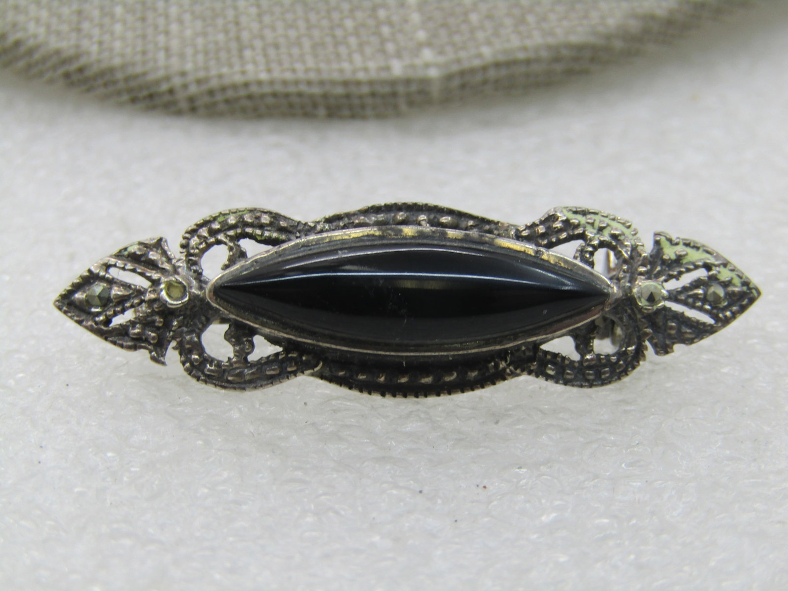 Vintage Sterling Onyx Marcasite Brooch, 1.5" by 1/2": Vintage Sterling Onyx Marcasite Brooch, 1.5" by 1/2" . Cateye bezel set stone with open work frame with marcasites and a dotted design set lower than the stone framing the brooch. Marked sterling and 