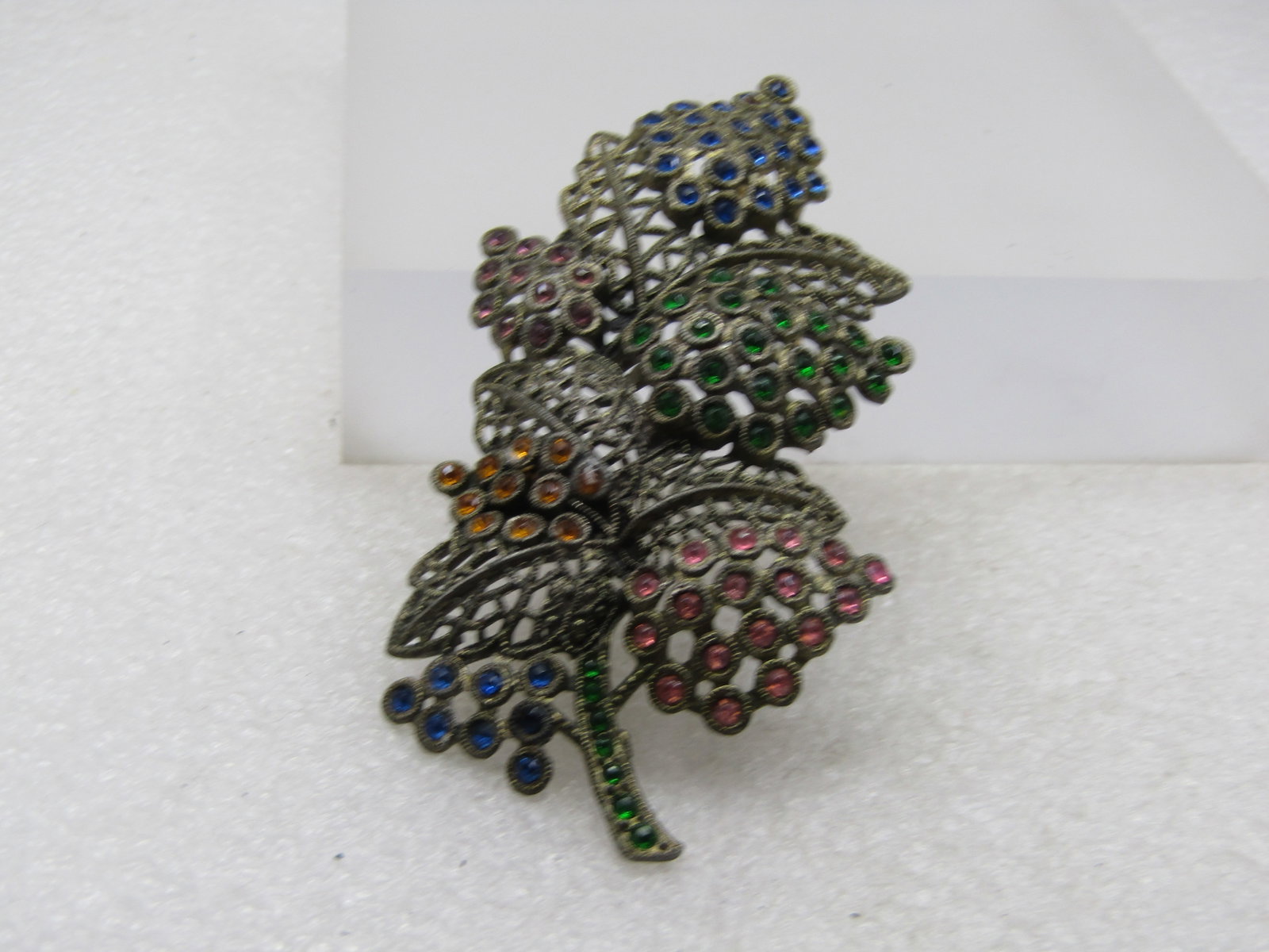 Vintage Rhinestone Stem Brooch, 3.5", 1920's-1930's. .: Vintage Rhinestone Stem Brooch, 3.5", 1920's-1930's. The brooch is a filigree desigh with tiered leaves and then blossom or leaf clusters with rhinestones - blue, green, pink,golden and a green stem. 