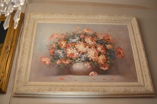 Vintage Floral Still Life Oil Painting in White Ornate Carved Frame: .Vintage Floral Still Life Oil Painting in White Ornate Carved FrameThis painting depicts a still-life of a white round vase. The vase contains a large bouquet of large pink flowers and green leaves.