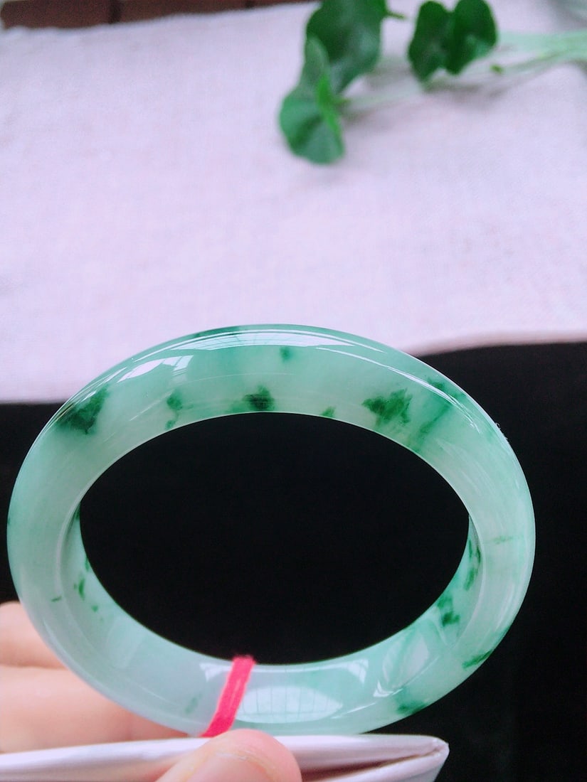 Ice Floating Flower Jadeite Bangle: Title: Ice Floating Flower Jadeite Bangle Description: This bangle showcases the unique charm of ice floating flower jadeite, with its watery and fine icy texture. Its perfect quality is captivating.