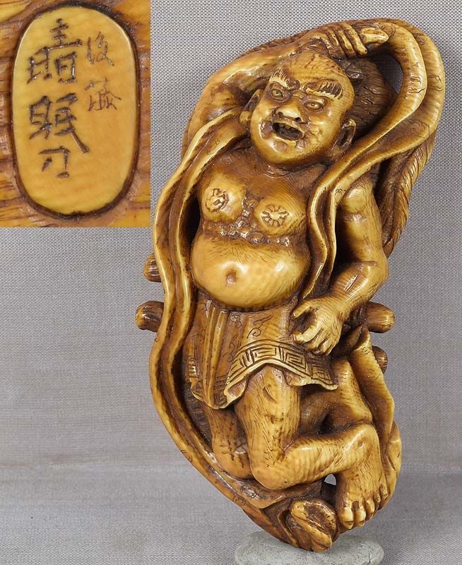 19c netsuke NIO on sandal by SEIMIN ex DU PONT 105mm: Unusually large 19th century netsuke of a Nio lying on a straw sandal. Nio - one of the Buddhist Guardian Kings - is holding a vajra in his right hand, and a scarf is laid out around him. Strong bold 