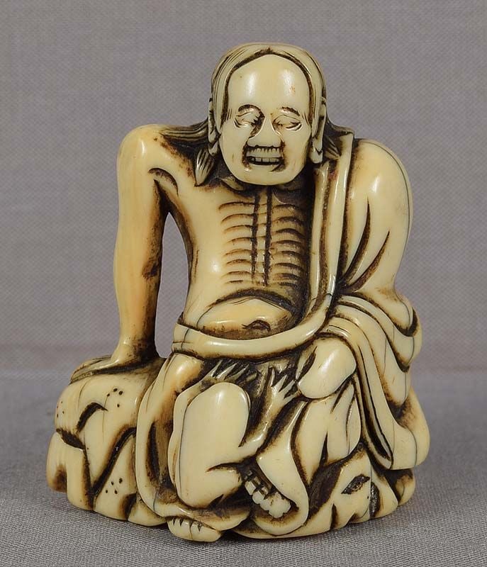 18c netsuke EMACIATED GAMA SENNIN with toad: 18th century netsuke of an emaciated Gama sennin wearing old monk’s robe with his ribs visible sitting on rockery as his constant companion - a toad - affectionately puts its paws on the manR