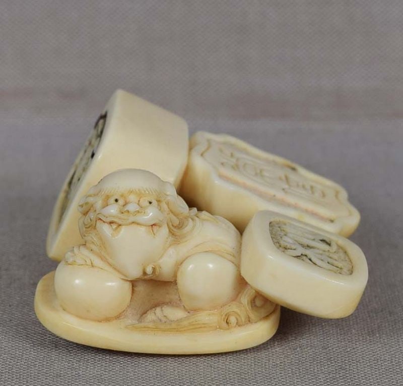 19c netsuke GROUP of SEALS: 19th century netsuke carved as a group of four seals - two of simpler shapes, one in a shape of a natural lotus flower stem (the stem serving as himotoshi), and one with shishi finial. Elegant design