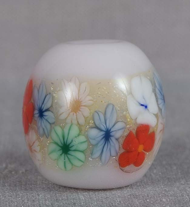 Japanese glass OJIME tombodama FLOWER BAND silver foil: Japanese glass ojime in a form of tombodama bead with milky white core and a band of multicolored flowers with fine tiny silver foil inclusions. Tombodama can be translated as “dragonfly ball