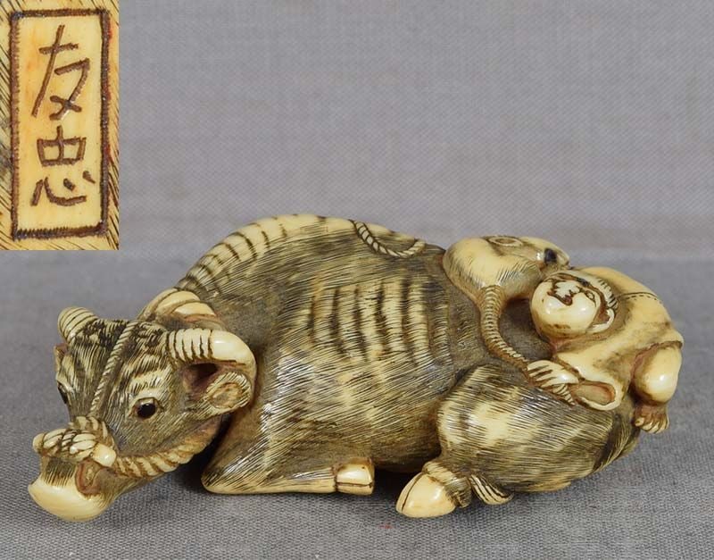 18c netsuke COW with BOY & RAT by TOMOTADA: Late 18th to early 19th century netsuke of a recumbent cow with a boy climbing on top of it while holding a rat by its tail. The netsuke is a reference to a Zodiac pairing of animals with an unusual a