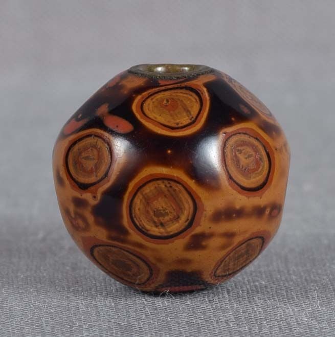 Unusual 19c lacquer OJIME netsuke slide: Unusual 19th century lacquer ojime (slide bead for tightening the cord going from netsuke to inro) of seed shape with faceted surface showing variously colored layers of lacquer from which the piece