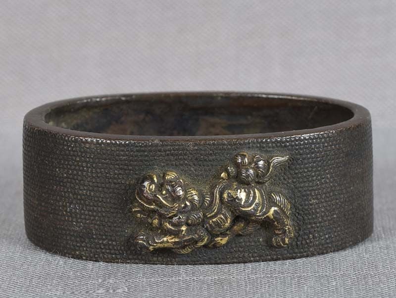 19c Japanese sword FUCHI playful shishi: 18th to early 19th century Japanese sword fuchi (bordering piece between the sword guard and the handle) with gilded relief design of playful shishi (Buddhist lion), all on finely punched ground
