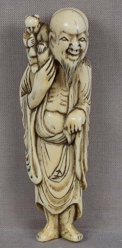18c netsuke SENNIN with BOY & trumpet 91mm: Good size 18th century netsuke of a standing sennin (Chinese sage) in a long robe and a leaf cape, carrying on his shoulder a Chinese boy who plays a short trumpet. The netsuke is probably a joke on t