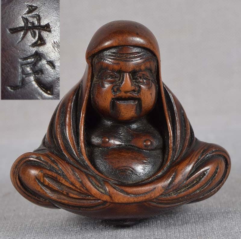 19c netsuke DARUMA by Hara SHUMIN: 19th century boxwood netsuke of the Zen Patriarch Daruma sitting in meditative pose enveloped in his monastic robe with cape. Great carving, fantastic face, beautiful flow to the lines of his robe, su