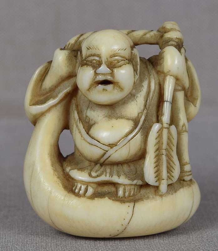 Early 19c netsuke HOTEI on bag: Early 19th century netsuke of Hotei (one of the 7 Gods of Good Luck, also representing Maitreya - the Buddha of the future) holding a fan in his hand and standing on his large bag of gifts. Wonderful 