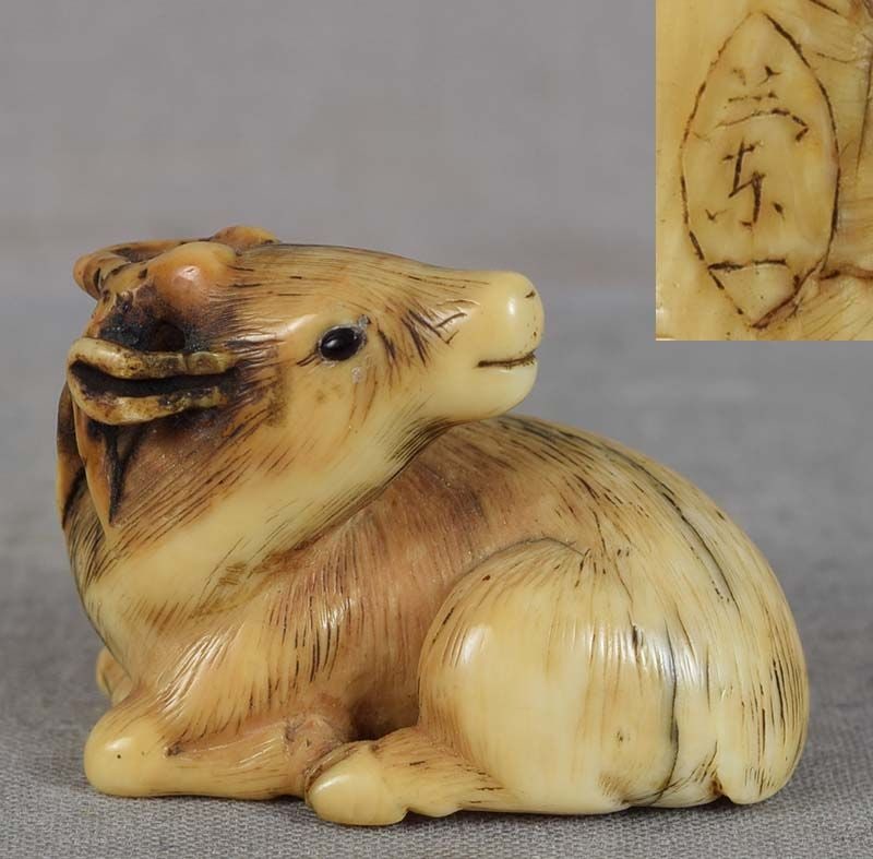19c netsuke resting DEER by RANICHI: 19th century netsuke of a reclining deer with its head turned back, hooves bent beneath its body. Elegant carving with pure clean lines, excellent hairwork, wonderful depiction of volume of the deer b