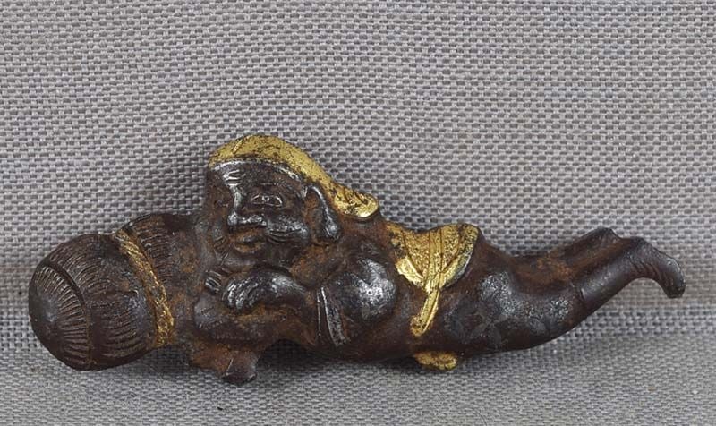 19c Japanese MAE-KANAGU pouch clasp DAIKOKU rice bale: 19th century Japanese iron mae-kanagu (tobacco pouch clasp fitting) depicting God of Abundance Daikoku resting by a bale of rice, his hammer in his hands. Iron is notoriously difficult to work with. V