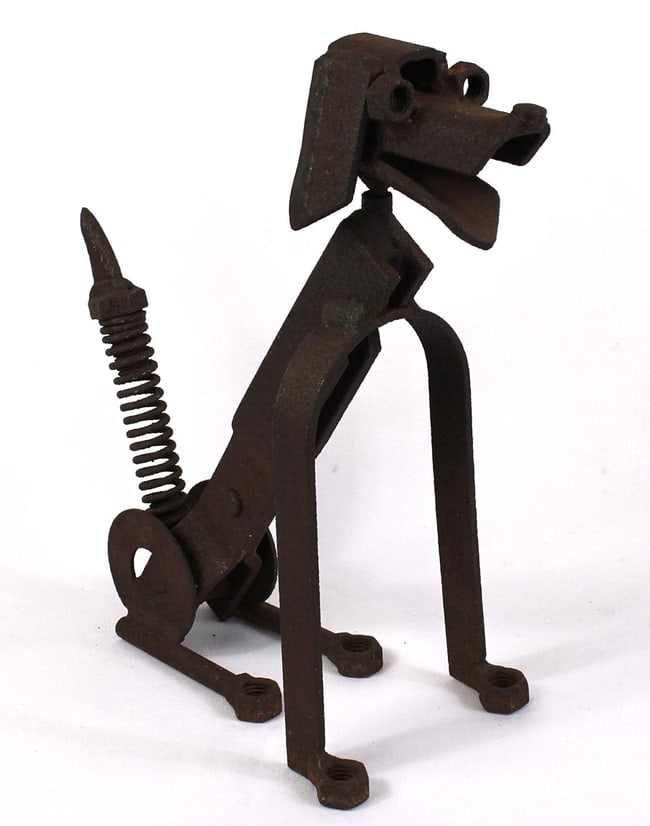 A folk art dog sculpture made from iron found objects.: This is a dog sculpture made from iron found objects. The head turns from side to side, and the tail is a spring that wags. It has large nuts for eyes and feet, and looks like a happy dog. The