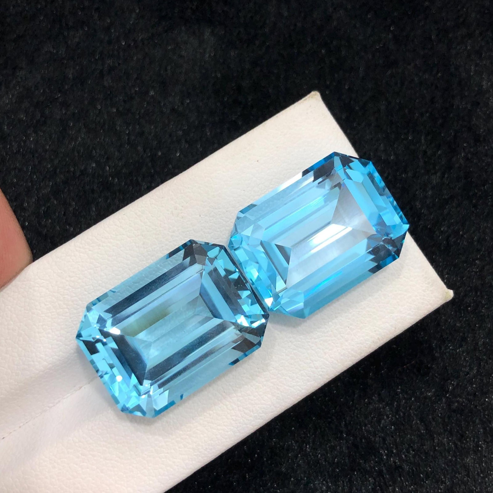 Emerald Cut Swiss Blue Topaz Pair: November Birthstone, 72.70 Carat: Introducing a magnificent Swiss Blue Topaz gemstone. Its long emerald shape, which sparkles wonderfully, stands for prosperity and love. This jewel is exquisitely carved and emanates grace and charm. 