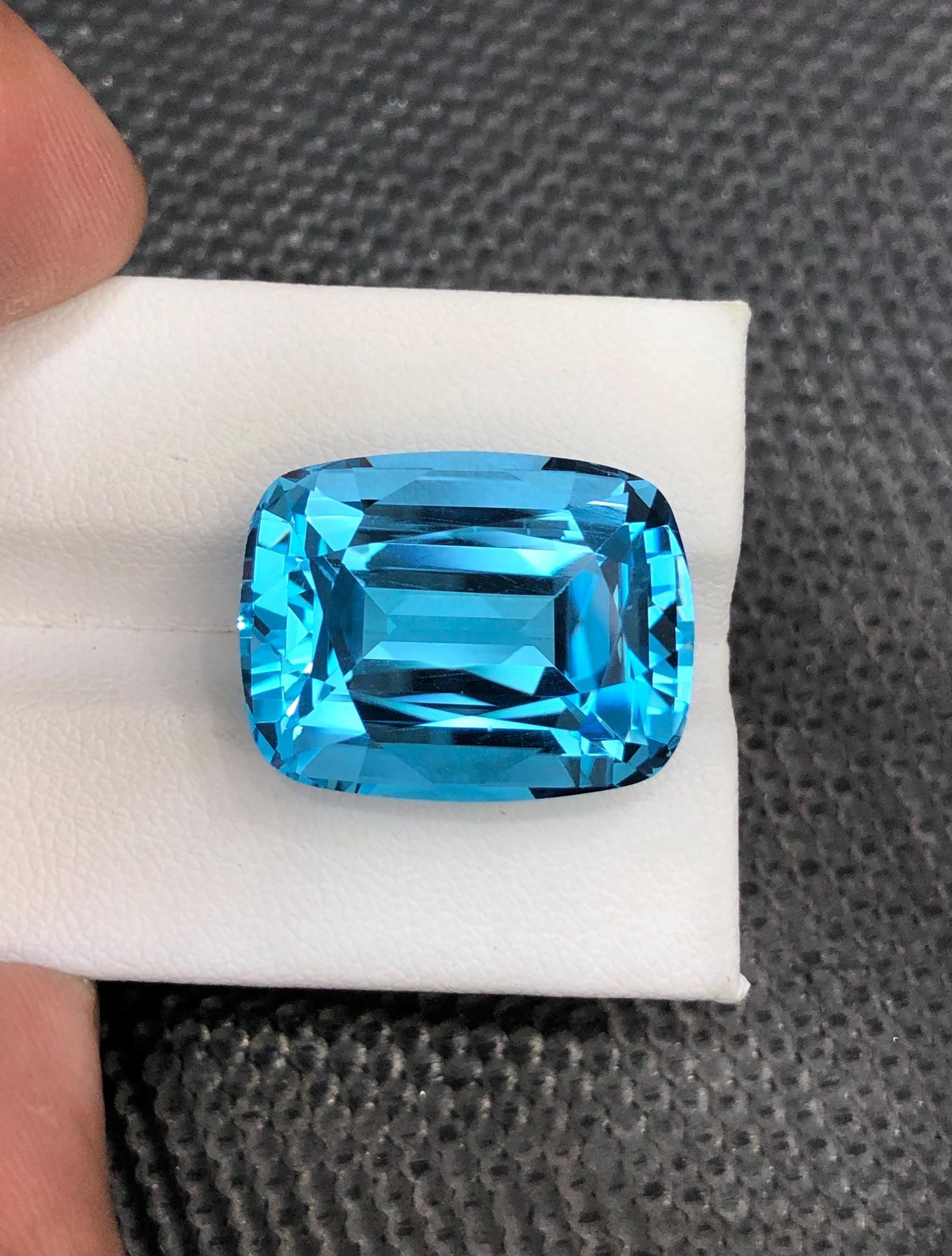 34.30 Carat Swiss Blue Topaz Gemstone: Cushion Cut December Birthstone: Introducing a magnificent Swiss Blue Topaz gemstone. Its long cushion shape, which sparkles wonderfully, stands for prosperity and love. This jewel is exquisitely carved and emanates grace and charm. 