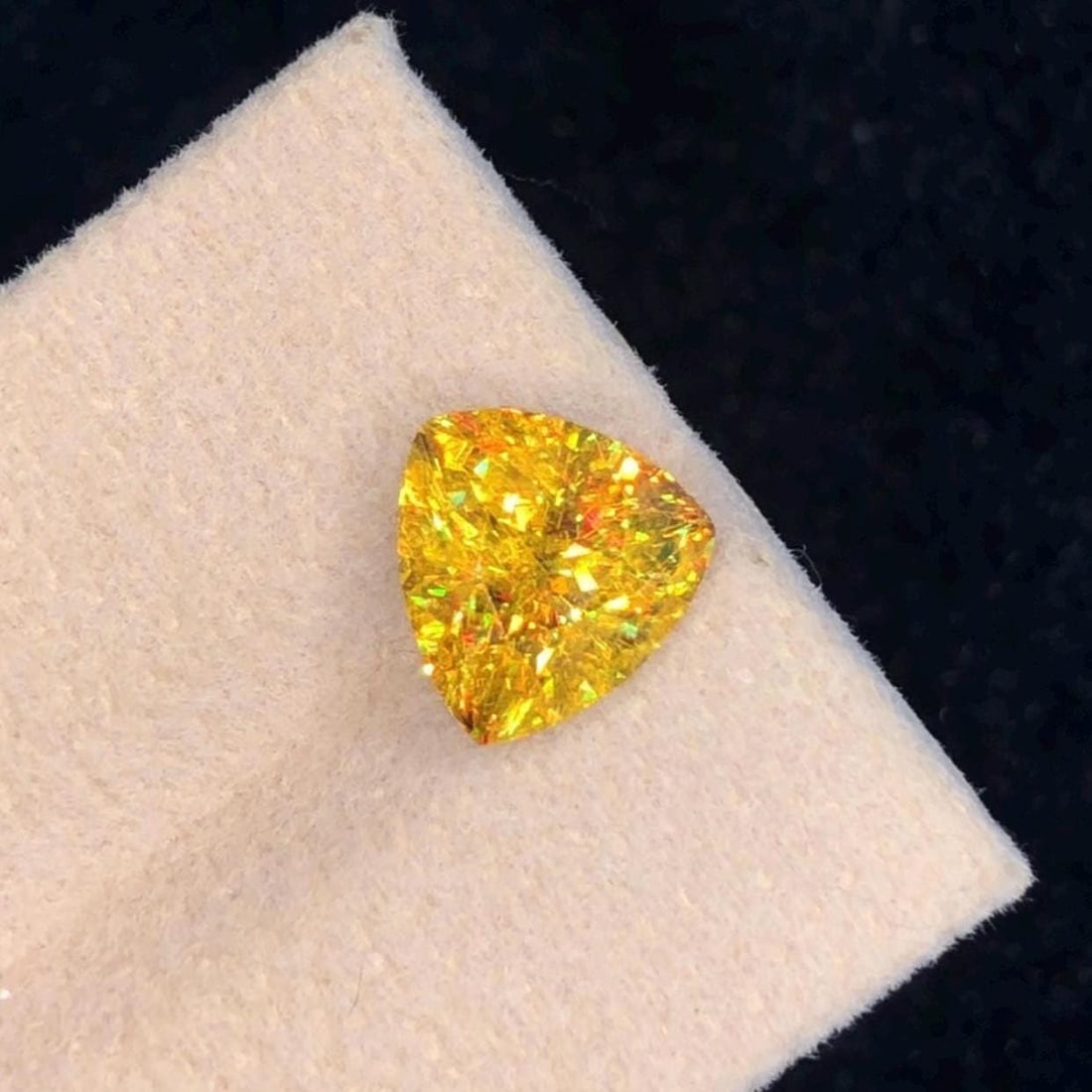 Trillion Cut Sphene Titanite Gemstone: Yellow Orange, 3.830 Ct: This stunning full fire sphene titanite loose gemstone features a captivating Trillion cut that enhances its brilliance and beauty. With its vibrant play of colors and exceptional clarity, this