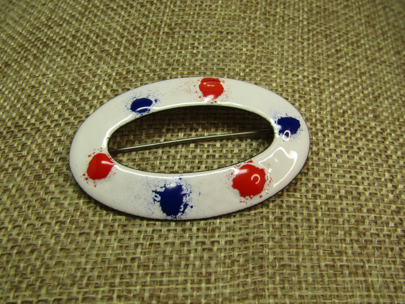 Vintage Red/White/Blue Enameled Brooch, 1960's: Vintage Red/White/Blue Enameled Brooch, 1960's. This is an open elongated oval with what background and splattered blue and red splotches around the oval - alternating. The brooch is appx.2" wide adn