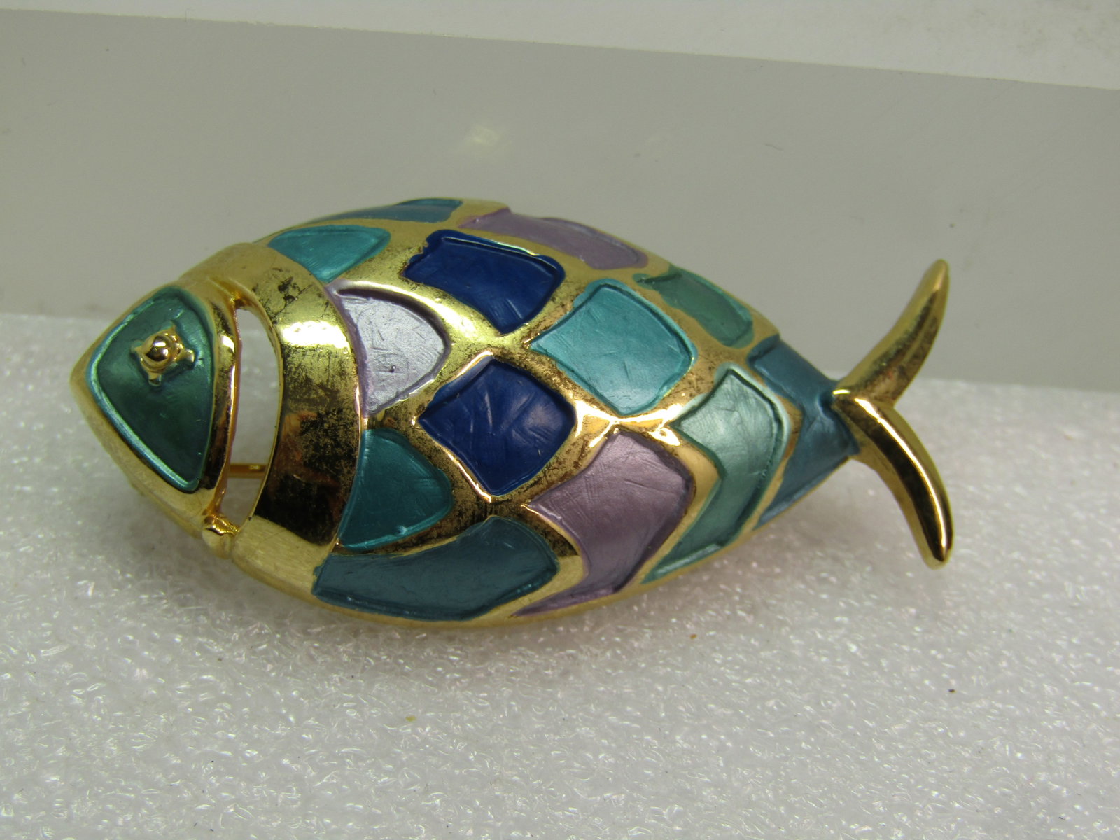 Vintage Enameled Fish Brooch, Lavender/Aqua, 1970's-1980's: Vintage Enameled Fish Brooch, Lavender/Aqua, 1970's-1980's. The fish is gold tone and facing left with recessed pearly enameling in aqua, lavender, and a dark purple/blue and lighter bue color. The fi