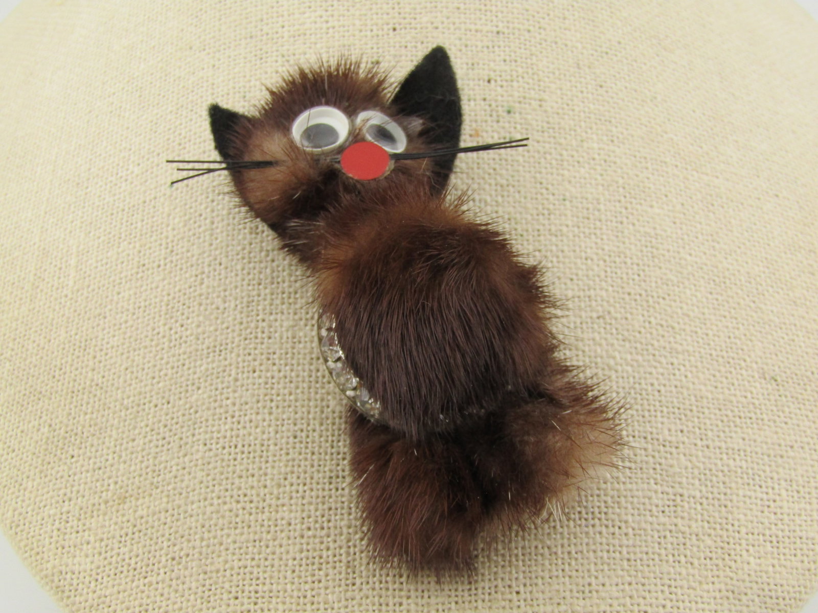 Hand Made Mink Cat Brooch with Rhinestone Accent, 1960's-1970's: Hand Made Mink Cat Brooch with Rhinestone Accent, 1960's-1970's. Brown fur with black felt ears, googly eyes, red nose and whiskers bat brooch. It has a round rhinestone circle from it's neck to the b