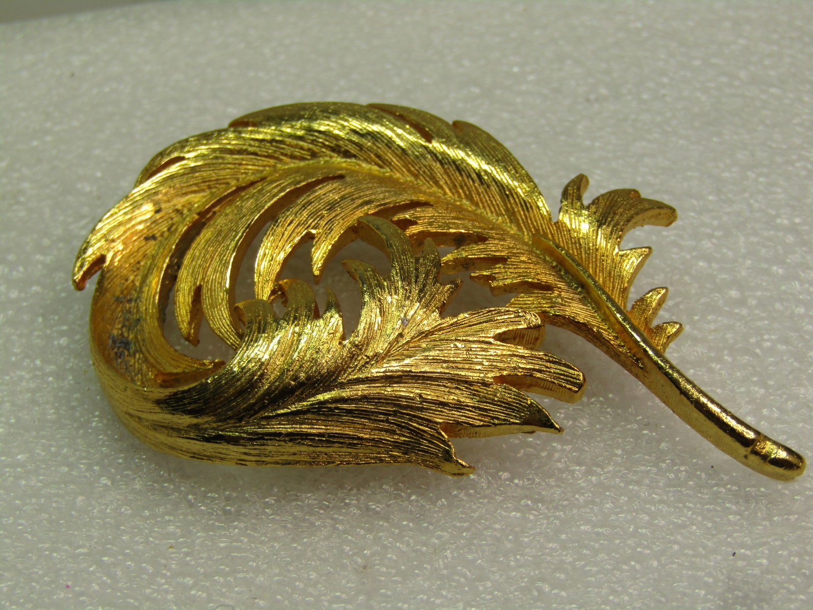 Vintage Gold Tone Feather Brooch, Curled/Curved, 1970's: Vintage Gold Tone Feather Brooch, Curled/Curved, 1970's. Gold tone and 2.5" tall and 1.5" wide. Textured finish, with locking clasp. Very good condition. It is not marked or signed. (NY2.3 SS15937 J