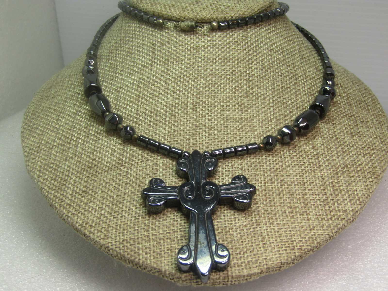 Hematite Carved Cross Beaded Necklace, 26", 1980's-1990's: Hematite Carved Cross Beaded Necklace, 26", 1980's-1990's. This has as appx. 2.5" by 1.75" hematite cross with barrel, round faceted, and angled beads. Barrel clasp. The beads range from appx. 4mm to 