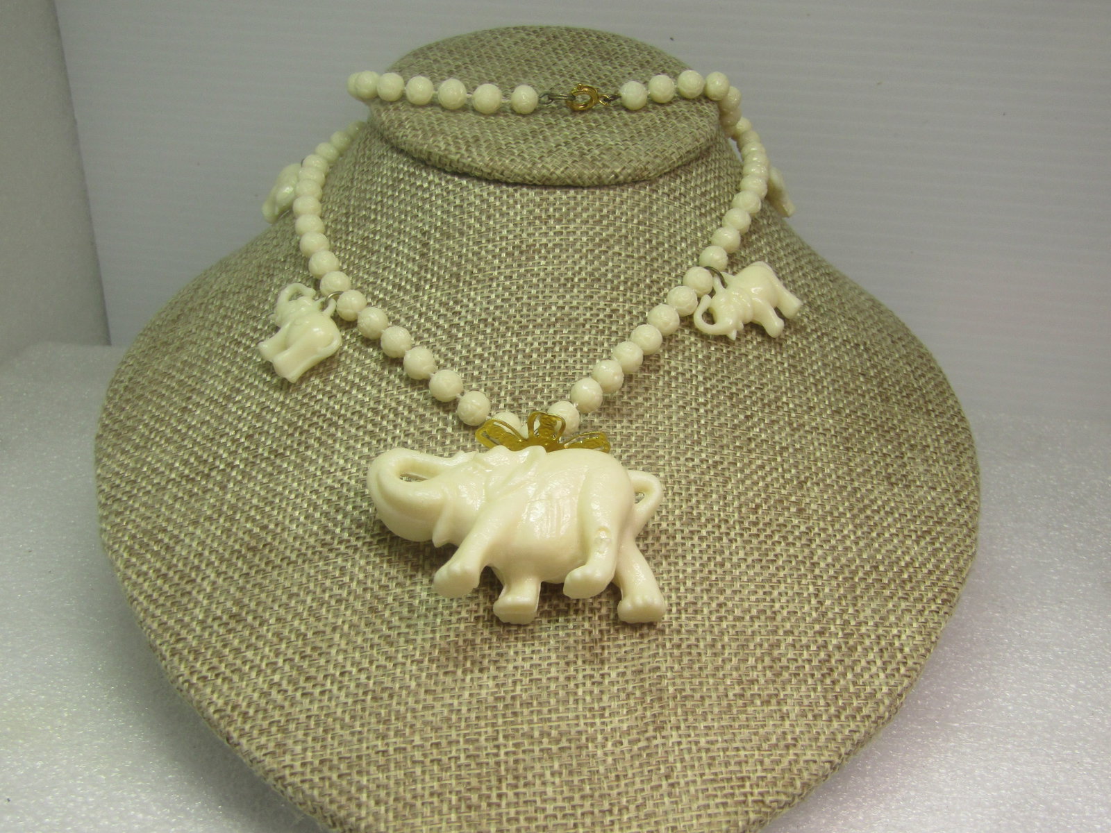 Vintage White Molded Elephant Necklace, Beaded, 24", 1970's-1980's.: Vintage White Molded Elephant Necklace, Beaded, 24", 1970's-1980's. The main elephant pendant is appx. 2" wide by 1.25" tall with a filigree gold tone blossom topper. The beads are molded beads that a