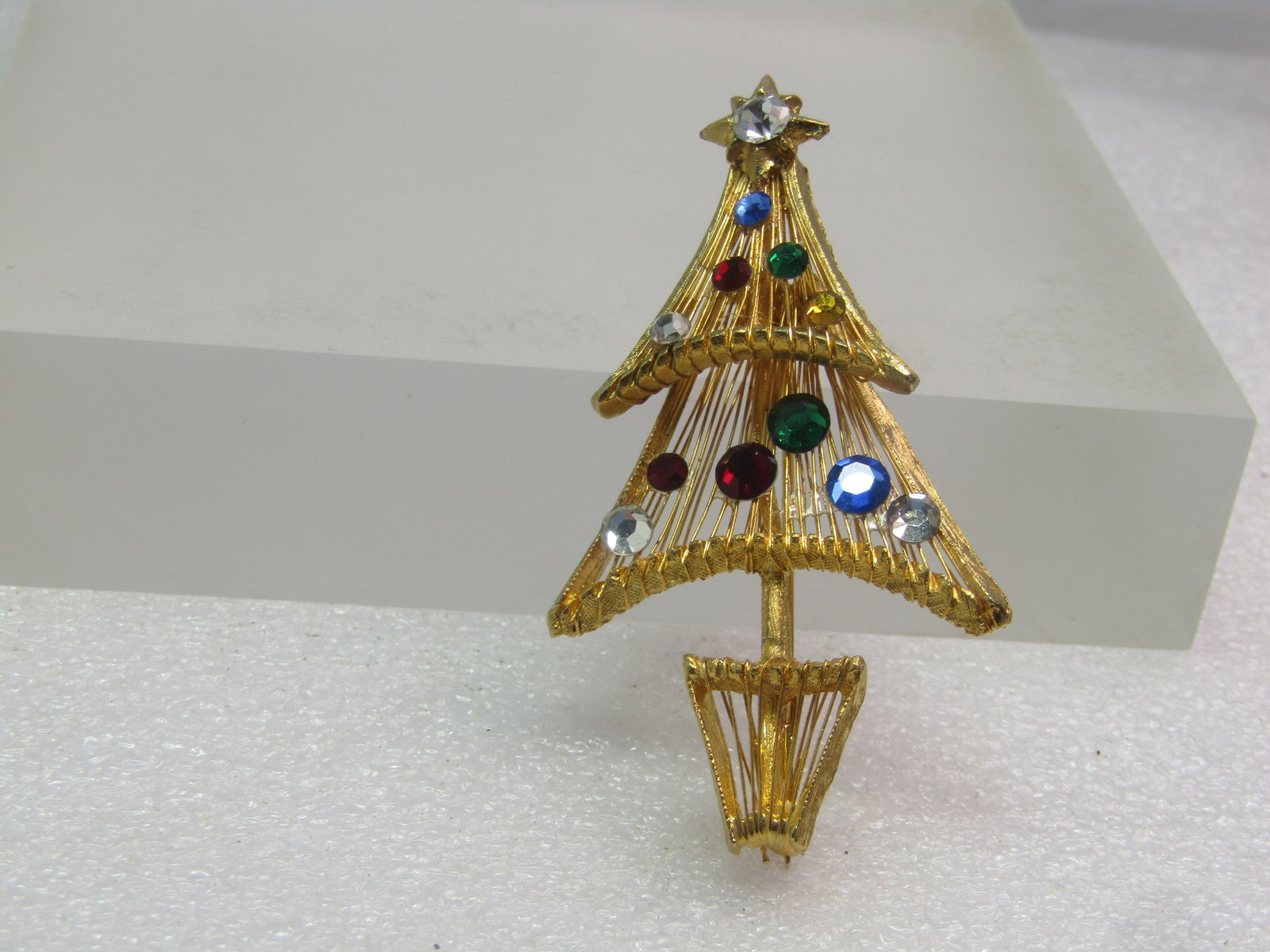 Vintage Rhinestone Christmas Tree Brooch, 1970's-1980's: Vintage Rhinestone Christmas Tree Brooch, 1970's-1980's. This has a clear stone set in a staron top. It is appx. 2.5" tall and 1.5" wide with two stacked tiers that have wiredd drops creating the bran