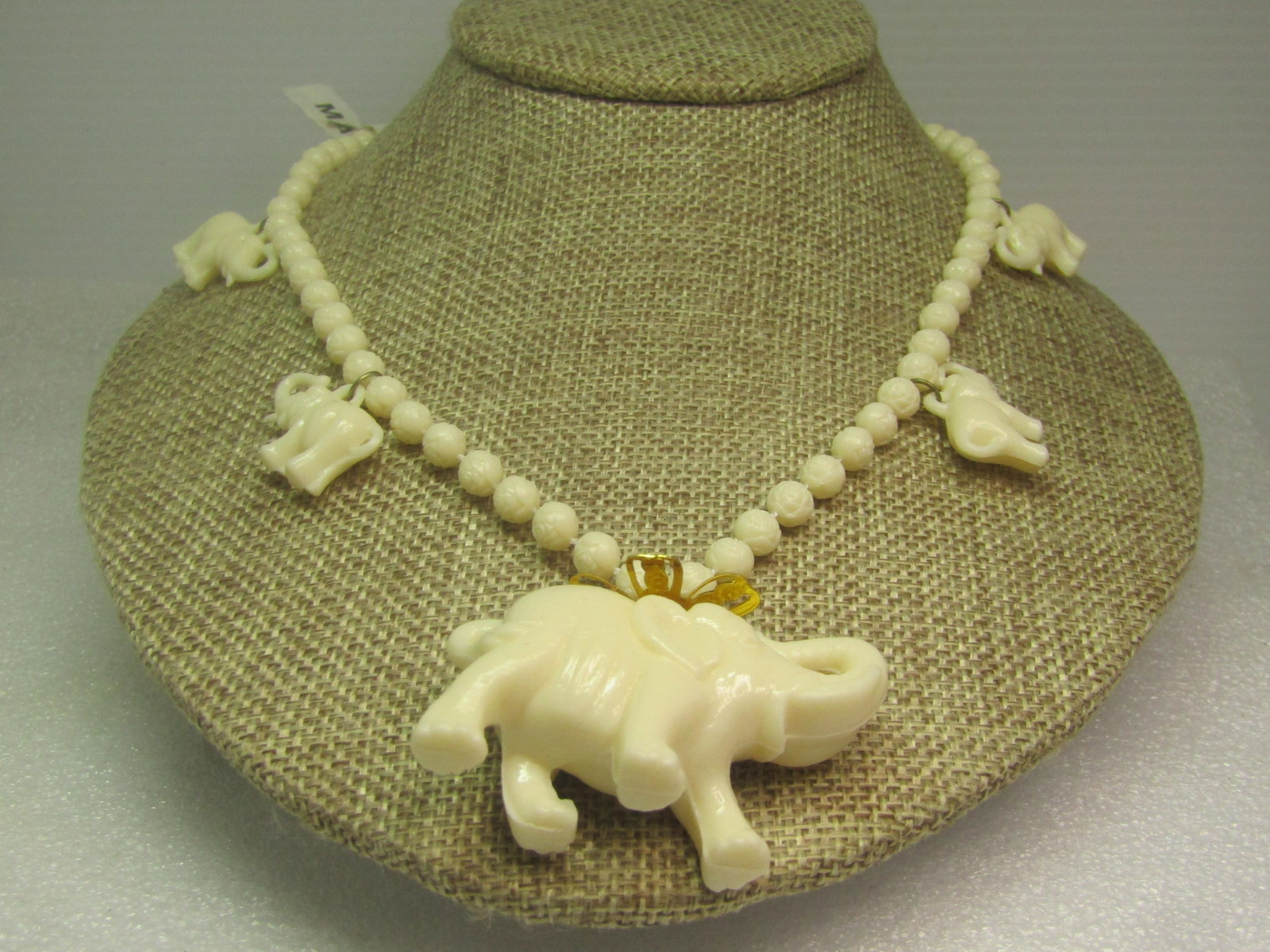 Vintage White Molded Elephant Necklace, Beaded, 24", 1970's-1980's.: Vintage White Molded Elephant Necklace, Beaded, 24", 1970's-1980's. The main elephant pendant is appx. 2" wide by 1.25" tall with a filigree gold tone blossom topper. The beads are molded beads that