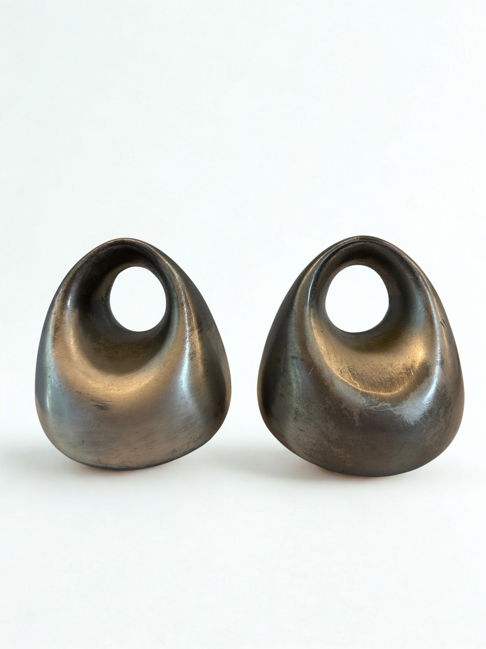 Pair of Mid-Century Modern Cast Metal Bookends by Ben Seibel for Raymor: A sophisticated pair of mid-20th century cast metal bookends, designed by Ben Seibel for Raymor. These sculptural bookends feature an organic, biomorphic form with a stylized tear-drop or kidney bean