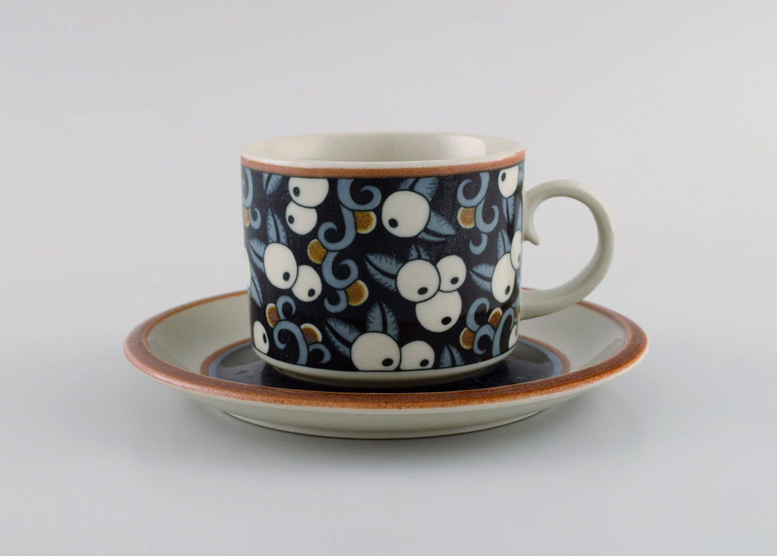 Inkeri Seppälä for Arabia. Taika morning cup with saucer in glazed stoneware decorated: Inkeri Seppälä for Arabia. Taika morning cup with saucer in glazed stoneware decorated with blue and white berries. 1970s. The cup measures: 8.5 x 7 cm. Saucer diameter: 16.5 cm. In