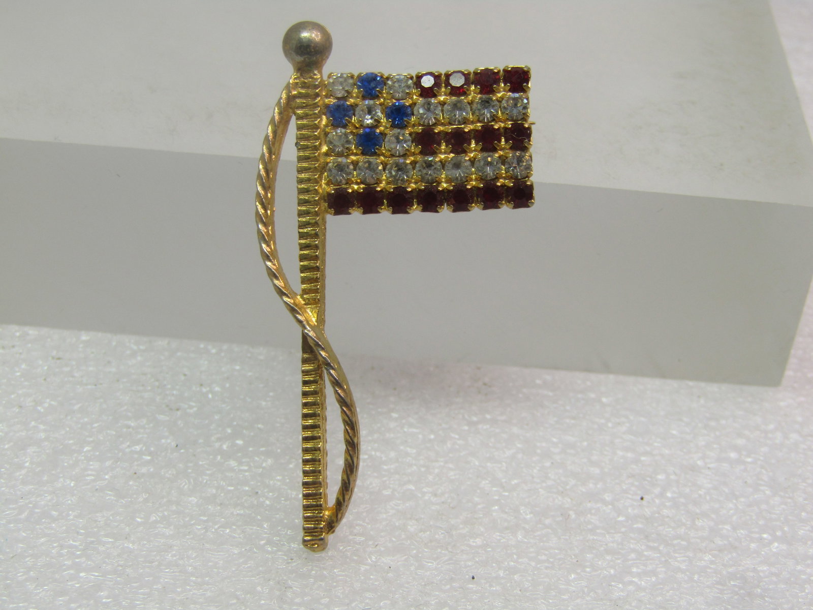 Vintage Red/White/Blue Rhinestone USA Flag Brooch, 1980's-1990's: Title: Vintage Red/White/Blue Rhinestone USA Flag Brooch, 1980's-1990's Description: Vintage Red/White/Blue Rhinestone USA Flag Brooch, 1980's-1990's. This is gold tone with flagpole and wrapping rope