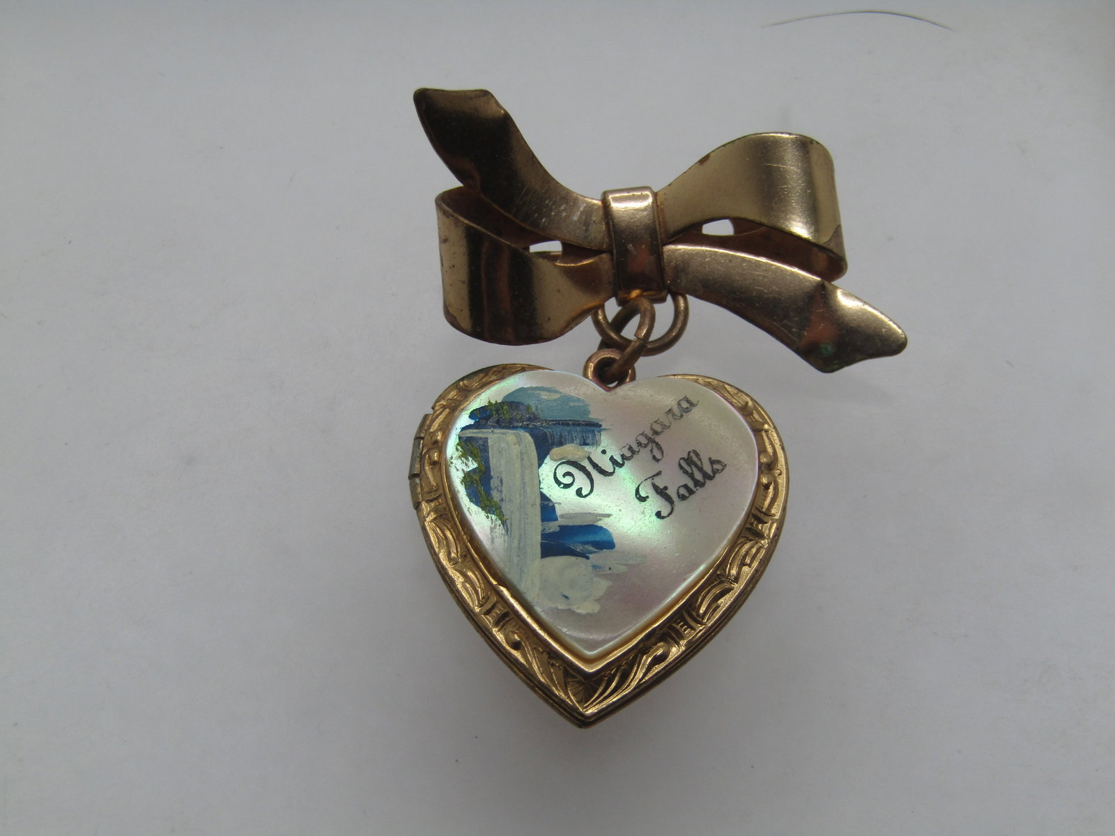 Vintage Niagara Falls Heart Locket & Bow Brooch, 1940's-1950's Souvenir.: Title: Vintage Niagara Falls Heart Locket & Bow Brooch, 1940's-1950's Souvenir. Description: Vintage Niagra Falls Heart Locket & Bow Brooch, 1940's-1950's. Souvenir brooch. Gold tone with a faux mothe