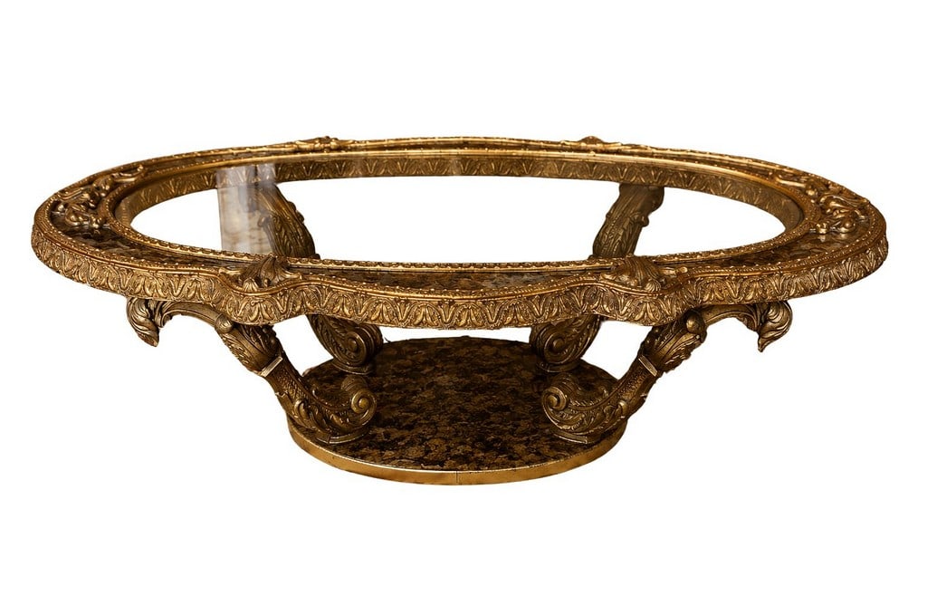 Giltwood Oval Glass Top Coffee Table: A striking giltwood coffee table, likely Italian and dating to the mid-20th century, executed in a Rococo Revival style. The oval form features a delicate glass top inset into a highly ornate carved