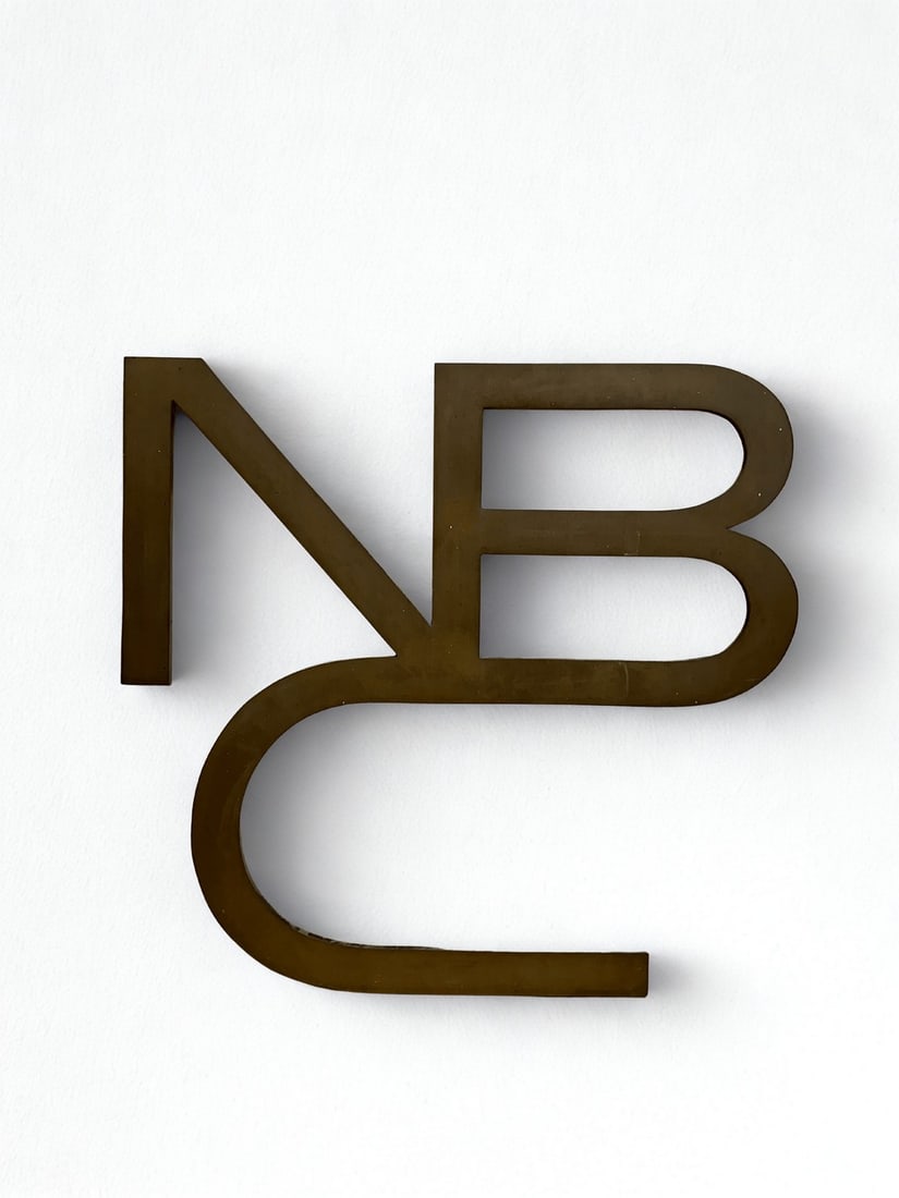 NBC Logo Dimensional Sign, Mid-20th Century: A mid-20th century dimensional sign featuring the stylized "NBC" logo. Crafted from patinated metal, this corporate signage would have originally adorned the exterior or interior of an NBC facility.