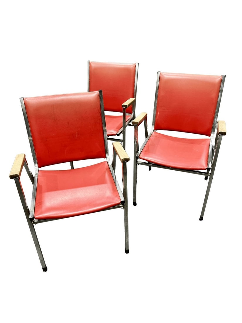 Set of Three Mid-Century Modern Armchairs: A set of three striking Mid-Century Modern armchairs, likely dating from the 1950s or 1960s. Each chair features a sleek, minimalist design with a chrome-plated tubular steel frame and vibrant red