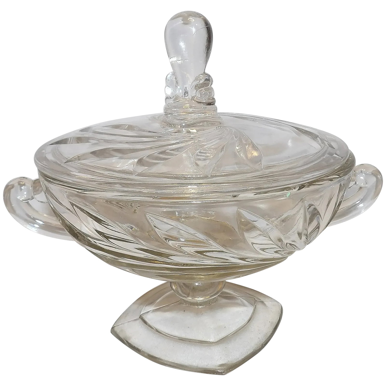 Vintage Clear Glass Round Pedestal Covered Candy Dish: This Vintage Clear Glass Round Pedestal Covered Candy Dish has 2 handles and laurel leaf cut glass design. Most likely MCM maker unknown. Has one small chip on the lip of the lid (see photo).